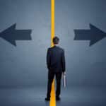 man in a suit holding a briefcase deciding which way to go, left or right, illustrating decision making
