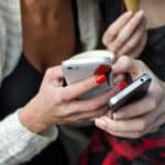 young women holding two phones indicating possible excessive smartphone use