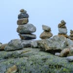 A family of stone tower statues piled on one big rock symbolizing resilience.
