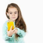 Photo of a young girl mesmerized by a yellow smartphone she is gazing at intensely.
