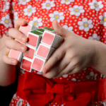 girl in red dress with flowers holding a Rubik's Cube puzzle