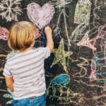 Child drawing on public chalkboard illustrates the use of storytelling in building resilience in children.