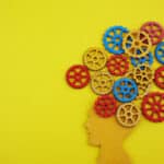 Illustration of a human head with colorful gears flowering from the top illustrating the universal mechanism of addiction in the brain.