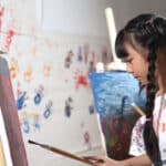 Playful student painting on canvas in art therapy.