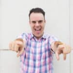 Photograph of a man in a striped shirt laughing at his own bad joke.