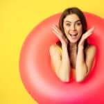 Photograph of a woman wearing a pink inflatable donut with a look of surprise symbolizing the weight gain from discontinuing GLP-1 drugs.