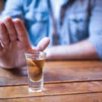 Photograph of a person refusing a drink of alcohol.