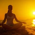 photograph of a woman meditating on the beach