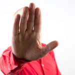 Photo of a man holding his hand in front of his face in a gesture of discontinuation.