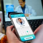 Close up photo of a hand holding a smartphone showing an online doctor visit with "Dr. John"