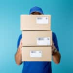 Photo of package delivery person holding three parcels in front of him which is symbolic of compulsive buying disorder.