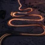 Aerial photograph of a twisty road at night illuminates a path similar to the way dopamine illuminates the brain's reward system.
