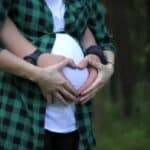 Man's and woman's hands on her pregnant belly.