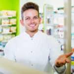 Photo of a pharmacist wearing uniform and working in pharmaceutical shop, representing the supply side of the opioid epidemic.