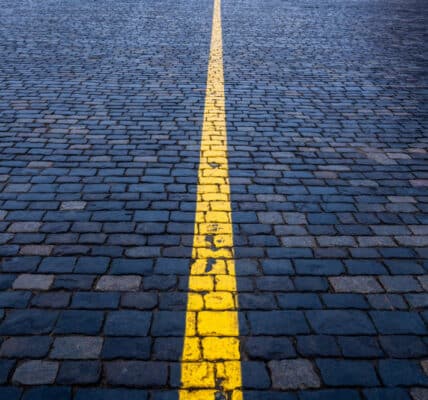 Photograph of brick paving, painted blue, with a yellow line down the center, indicated the line between substance use and substance abuse.