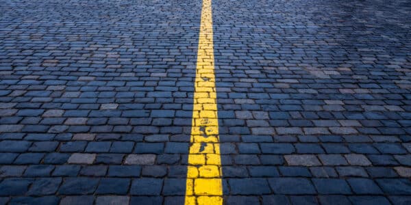 Photograph of brick paving, painted blue, with a yellow line down the center, indicated the line between substance use and substance abuse.
