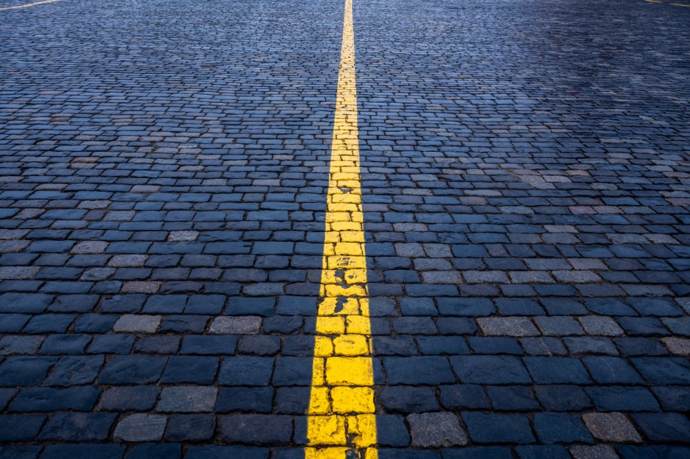 Photograph of brick paving, painted blue, with a yellow line down the center, indicated the line between substance use and substance abuse.