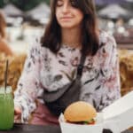 Photo of a young woman resisting the visual cue of a hamburger and picking up an organic smoothie instead.