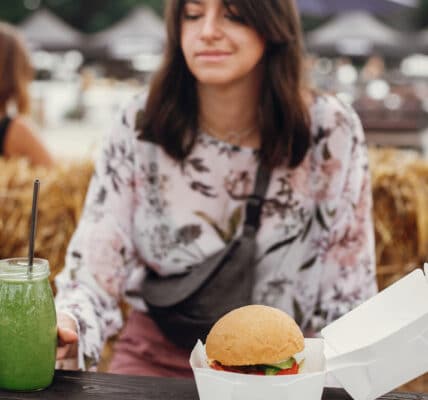 Photo of a young woman resisting the visual cue of a hamburger and picking up an organic smoothie instead.