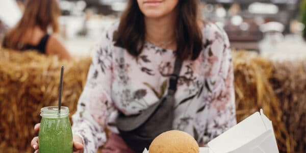 Photo of a young woman resisting the visual cue of a hamburger and picking up an organic smoothie instead.