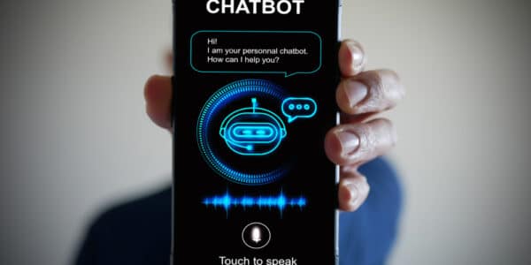 Photo of a hand holding smartphone with a digital AI chatbot on the screen.