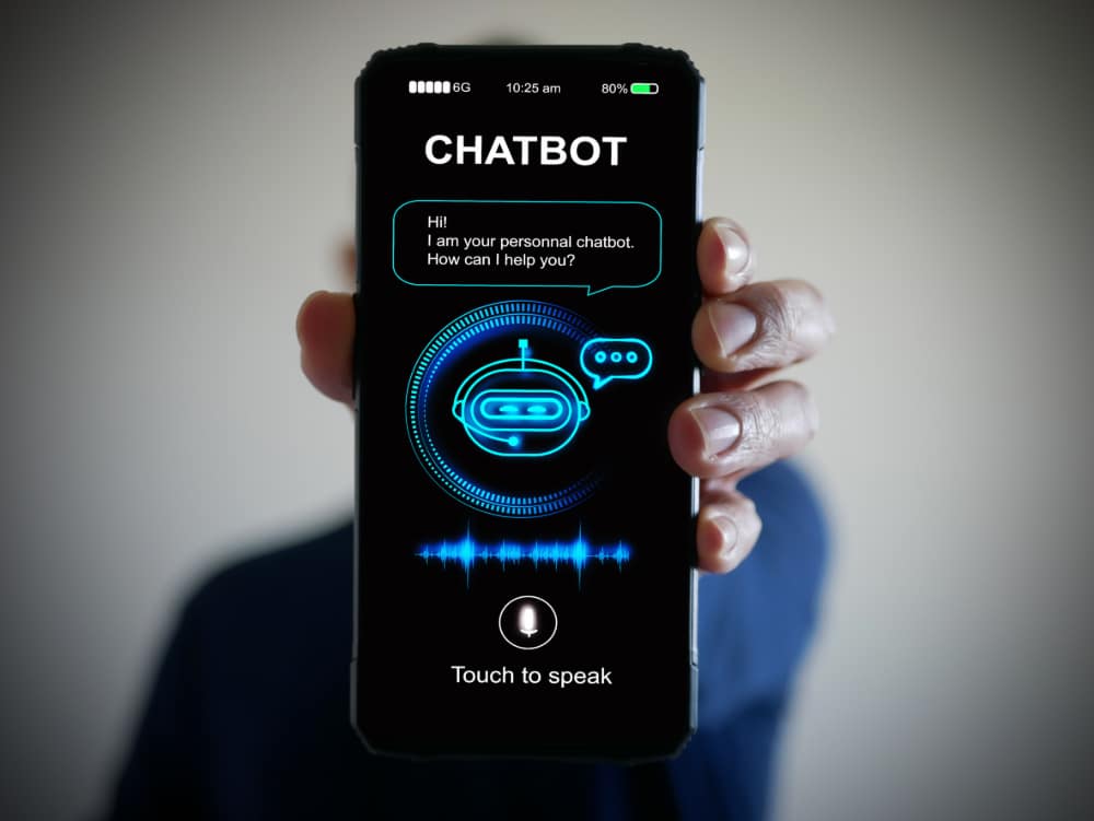 Photo of a hand holding smartphone with a digital AI chatbot on the screen.