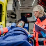 Photo of an overdose victim being loaded into an ambulance to be taken to the emergency room where she has a slim chance of being enrolled in an addiction treatment program.