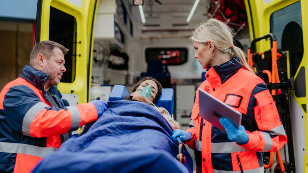 Photo of an overdose victim being loaded into an ambulance to be taken to the emergency room where she has a slim chance of being enrolled in an addiction treatment program.