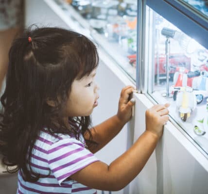 Photo of a young girl looking at blind box toys in a display window at a store.