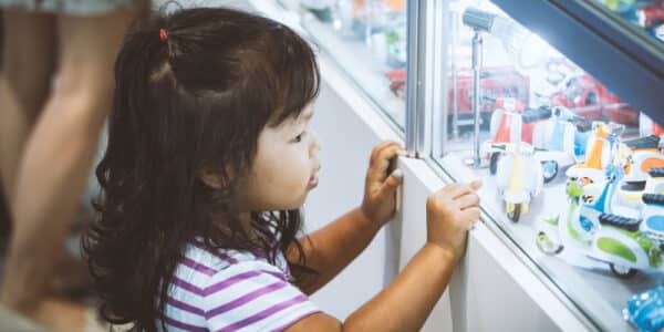 Photo of a young girl looking at blind box toys in a display window at a store.