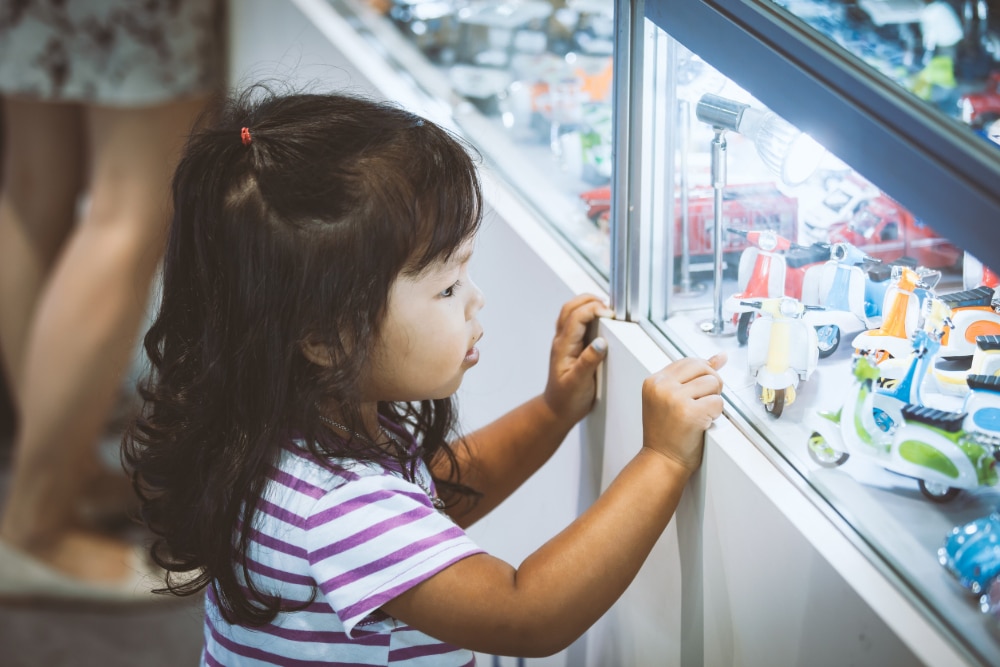 Photo of a young girl looking at blind box toys in a display window at a store.
