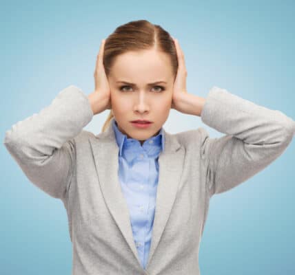 Photo of robotic-looking woman with her hands over her ears and an expression indicating cognitive dissonance.