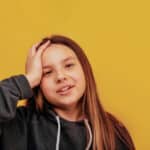 Photo of a girl with her hand on her head, a metaphor for brain size being associated with adolescent substance abuse.