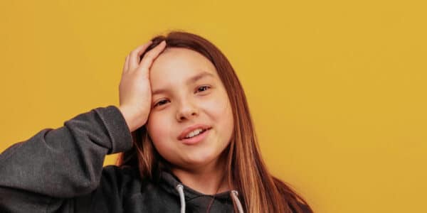 Photo of a girl with her hand on her head, a metaphor for brain size being associated with adolescent substance abuse.