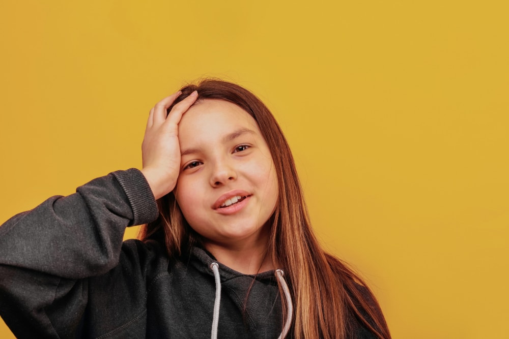 Photo of a girl with her hand on her head, a metaphor for brain size being associated with adolescent substance abuse.