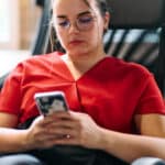 Photo of a seated woman using a therapy chatbot on her smartphone.