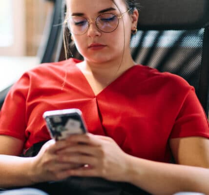 Photo of a seated woman using a therapy chatbot on her smartphone.