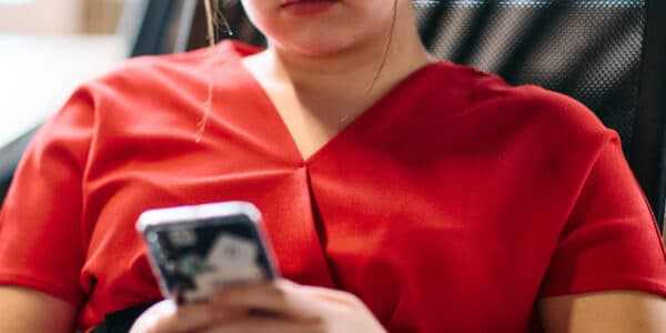 Photo of a seated woman using a therapy chatbot on her smartphone.