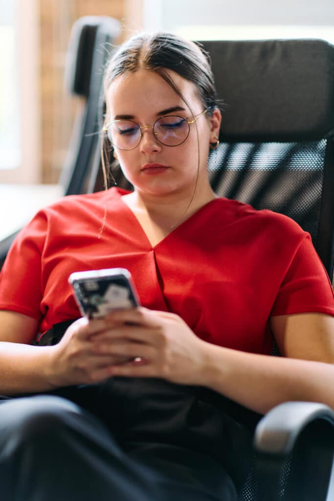 Photo of a seated woman using a therapy chatbot on her smartphone.