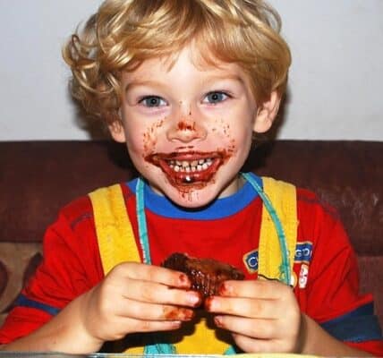 A kid with chocolate frosting smeared on his face.