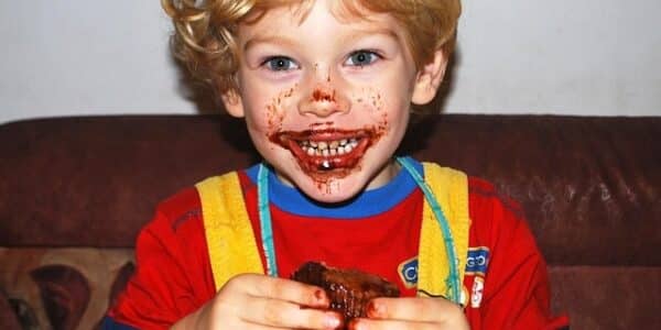A kid with chocolate frosting smeared on his face.