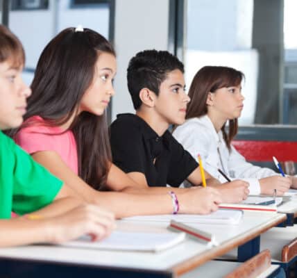 Photograph of teenage students at their desks in a classroom taking notes on a substance abuse prevention program.