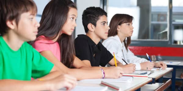 Photograph of teenage students at their desks in a classroom taking notes on a substance abuse prevention program.