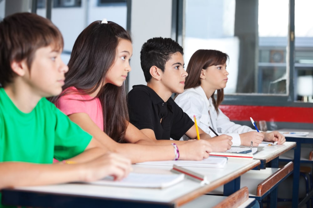 Photograph of teenage students at their desks in a classroom taking notes on a substance abuse prevention program.