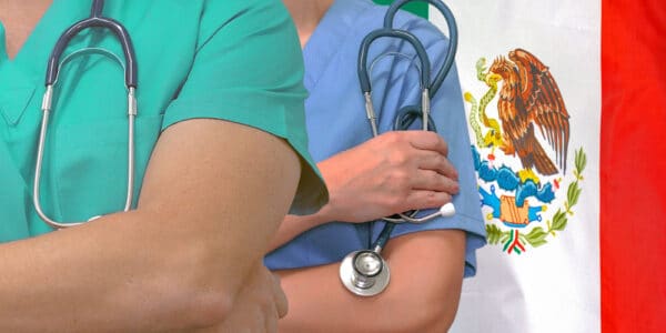Close-up photo of addiction treatment medical team man and woman with Mexico flag in background.