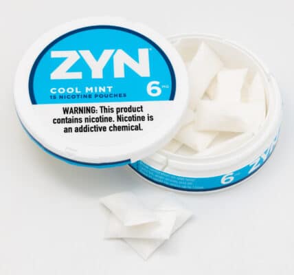 Photo shows an open can of ZYN Nicotine Pouches in Cool Mint flavor with three pouches stacked outside the tin.