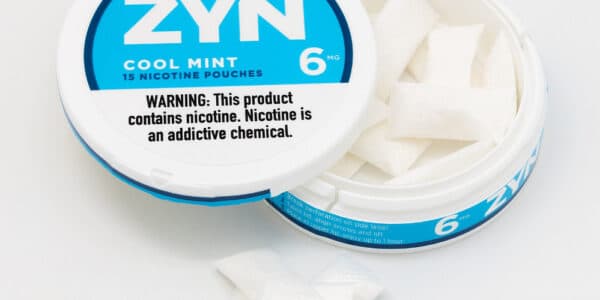 Photo shows an open can of ZYN Nicotine Pouches in Cool Mint flavor with three pouches stacked outside the tin.