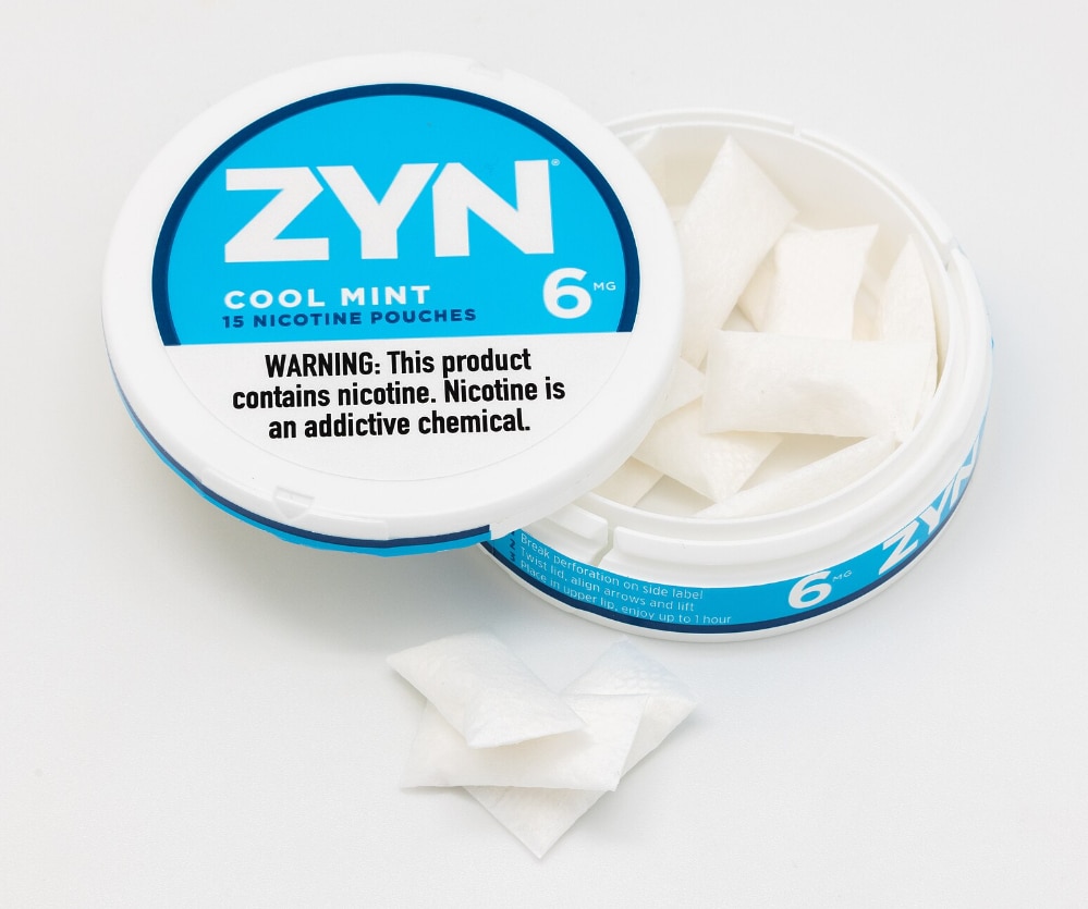 Photo shows an open can of ZYN Nicotine Pouches in Cool Mint flavor with three pouches stacked outside the tin.