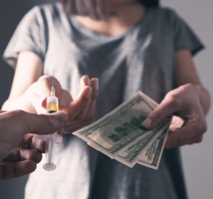 Photo of a woman exchanging a urine sample for payment as in a contingency management program.