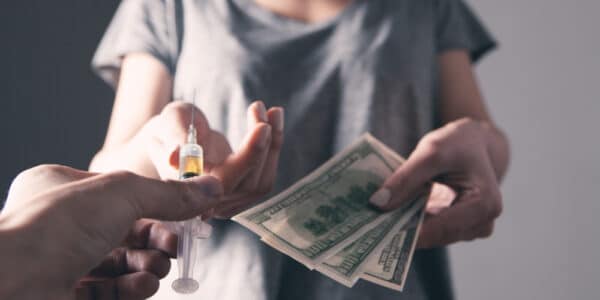 Photo of a woman exchanging a urine sample for payment as in a contingency management program.